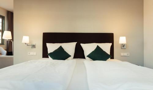 1 dormitorio con cama blanca y almohadas verdes en Zum Schwan Wanfried, en Wanfried