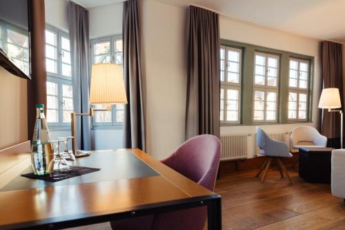 uma sala de estar com uma mesa, cadeiras e janelas em Zum Schwan Wanfried em Wanfried