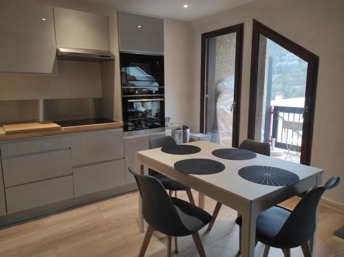 une cuisine avec une table et des chaises dans une pièce dans l'établissement Appartement vue montagne, cosy et chaleureux, à Briançon