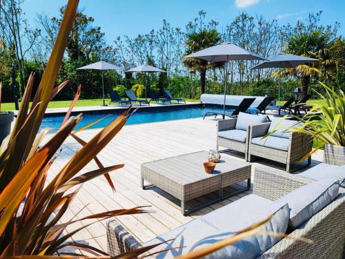 une piscine avec des chaises et des parasols à côté d'une piscine dans l'établissement Domaine des Hugons, à Prignac-et-Marcamps