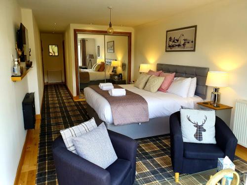 um quarto com uma cama grande e 2 cadeiras em Tower Ridge House em Fort William