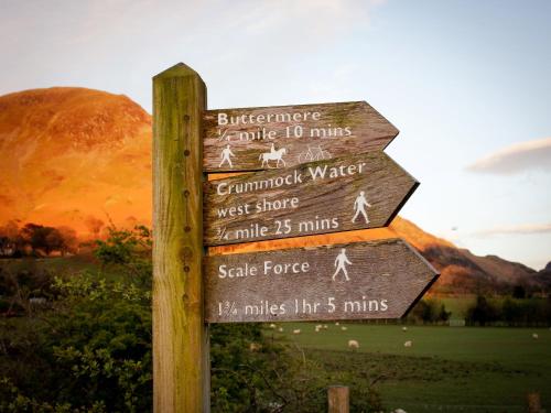 a sign with arrows on it with a mountain in the background at Buttermere Court Hotel in Buttermere