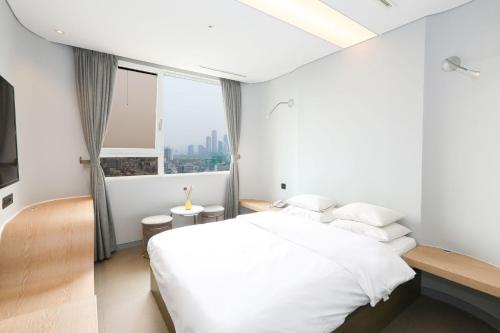 a white bedroom with a large bed and a window at Hotel The Designers Hongdae in Seoul