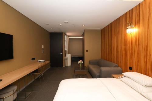 a hotel room with a bed and a chair and a television at Hotel The Designers Hongdae in Seoul