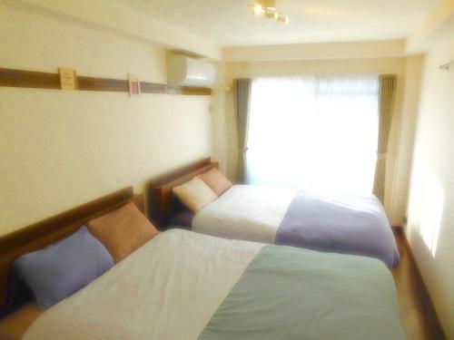 a hotel room with two beds and a window at SONIC APARTMENT HOTEL in Dazaifu