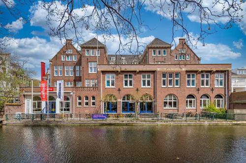 un grand bâtiment en brique à côté d'une masse d'eau dans l'établissement Stayokay Hostel Den Haag, à La Haye