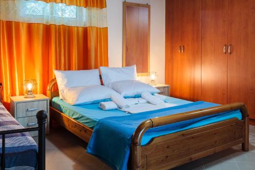 a bedroom with a bed with blue sheets and white pillows at Makarounis Athanasios Traditional Apartments(Ξενώνας) in Petalidhion