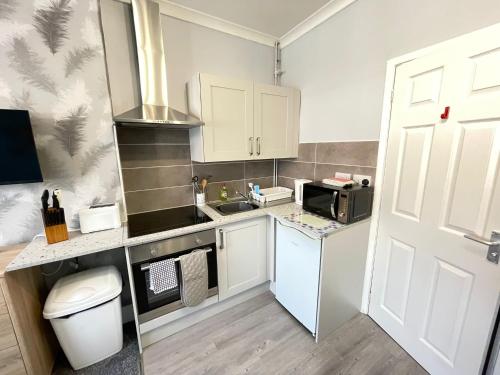 a small kitchen with a sink and a microwave at Large Ground Floor Studio Holiday Apartment Skegness - Flat 12 in Skegness