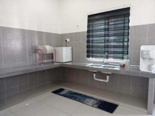 a kitchen with a counter and a sink and a window at HOMESTAY IMPIAN, BATU GAJAH PERAK in Kampong Paya Rengas