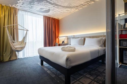 Habitación de hotel con cama y silla colgante en ibis Almaty Jetisu, en Almaty