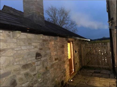 a stone building with a wooden door and a fence at Salcombe Holiday Cottage in Wilpshire