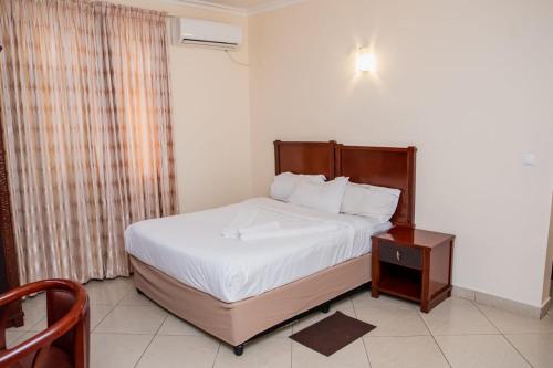a bedroom with a large bed and a night stand at Pensao Marhaba Residencial in Maputo