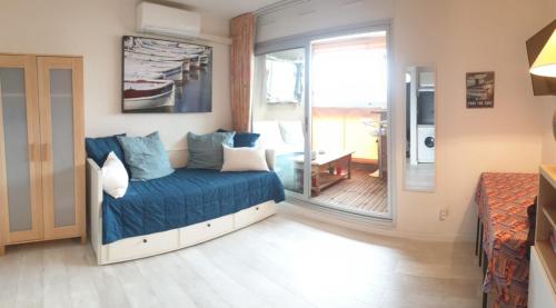 Un dormitorio con una cama con sábanas azules y una ventana. en FACE MER ENTRE PLAGE ET MARINA, en Bormes-les-Mimosas