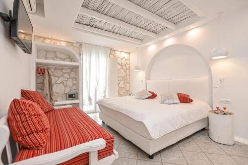 a bedroom with a white bed and a red chair at Naxos Evilion Luxury Apartments & Suites in Naxos Chora