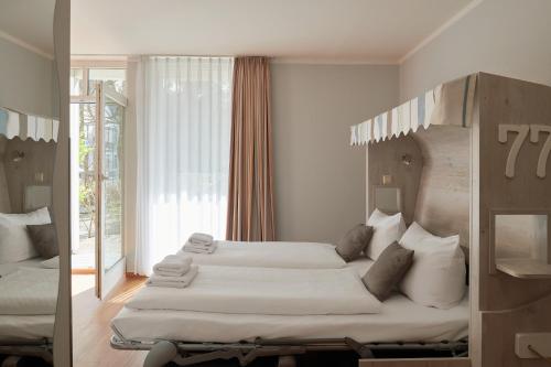 a bedroom with two beds and a large window at R&R Hotel Strandallee in Baabe