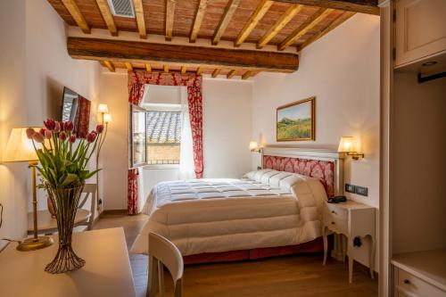 a bedroom with a bed and a table and a window at Palazzo del Mercante in Montepulciano