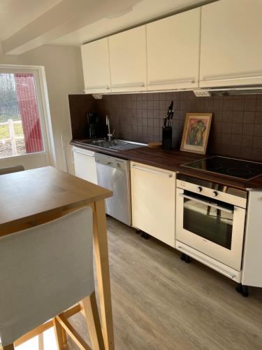 a kitchen with white cabinets and a stove top oven at Grindhuset in Skottorp