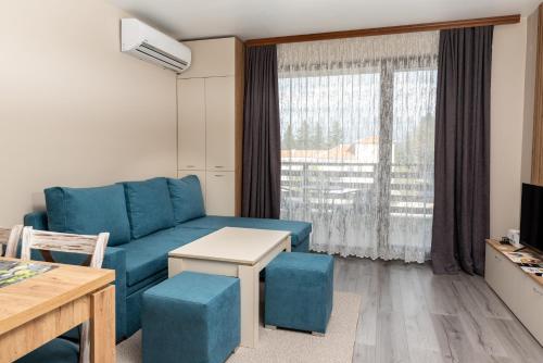 sala de estar con sofá azul y ventana en City Apartments 2, en Velingrad