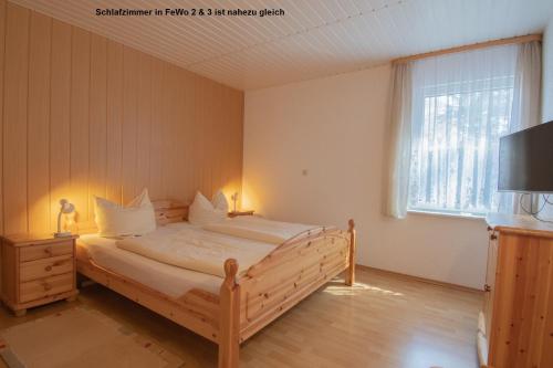 1 dormitorio con cama de madera, TV y ventana en Dünenhaus Fewos - Zum Strand 50m en Ueckeritz