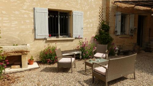 een patio met stoelen, een tafel en een raam bij LE CABANON in Crillon-le-Brave