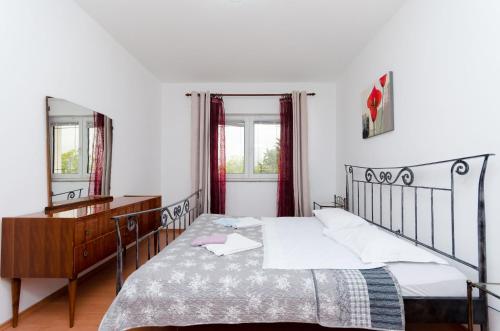 RakaljにあるApartments Milanのベッドとドレッサーと鏡のある寝室