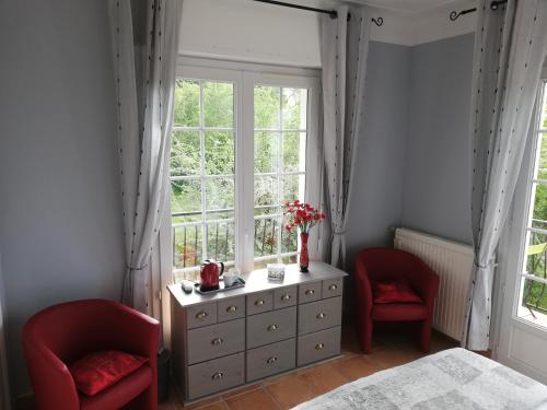 ein Schlafzimmer mit zwei roten Stühlen, einer Kommode und einem Fenster in der Unterkunft LESSENCIEL in Tournay