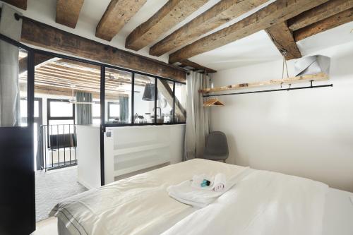 um quarto com uma cama branca e uma grande janela em Apartment Saint Germain des Prés by Studio prestige em Paris