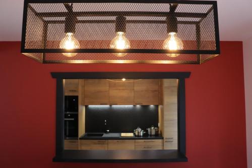 un miroir avec trois lumières sur un mur rouge dans l'établissement Gîte les Pervenches avec Sauna, à Gérardmer