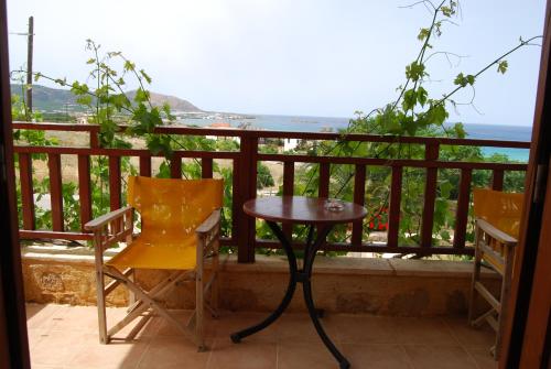 einen Tisch und Stühle auf einem Balkon mit Meerblick in der Unterkunft Golden Sun Apartments in Phalasarna