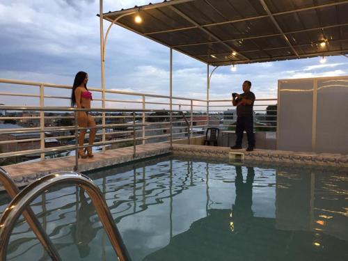 Un uomo che scatta una foto a una donna in piedi accanto alla piscina di Tarapoto Hostal *** a Iquitos
