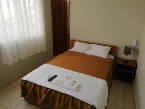 a bedroom with a bed with a remote control on it at Tarapoto Hostal *** in Iquitos