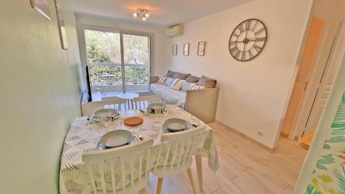 - un salon avec une table, des chaises et une horloge dans l'établissement Golfe Bleu, à Sainte-Maxime
