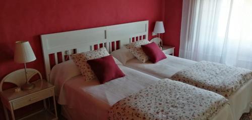 two beds in a bedroom with red walls at Cosy 2 bedroom cottage in mountain village in Loma Somera
