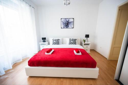 a white bedroom with a red blanket on a bed at Bright and Modern 1BDR Apartment in the Center in Sarajevo