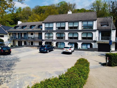 a large building with cars parked in a parking lot at Hof van Slenaken - Hotel & Apartments in Slenaken