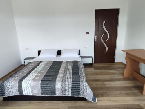 a bedroom with a bed and a wooden floor at Agropensiunea Olteanu in Niculiţel