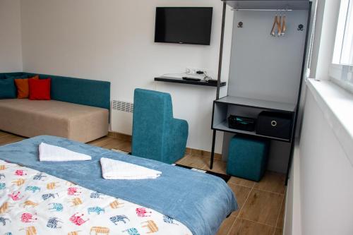 a room with a bed and a couch and a tv at Ravne Energy Apartments in Visoko
