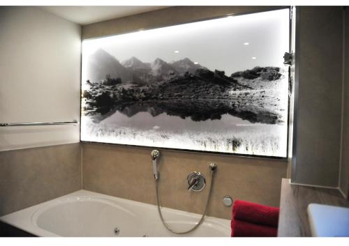 a bathroom with a bath tub with a picture on the wall at Bergpanorama in Oberstdorf