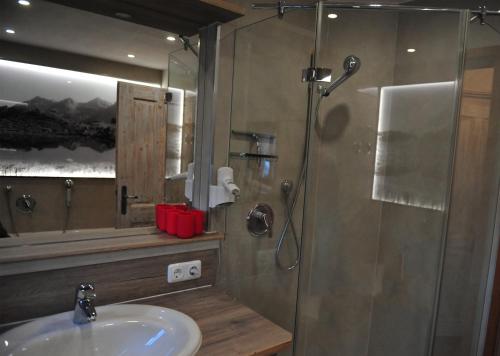 uma casa de banho com um lavatório e um chuveiro com um espelho. em Bergpanorama em Oberstdorf