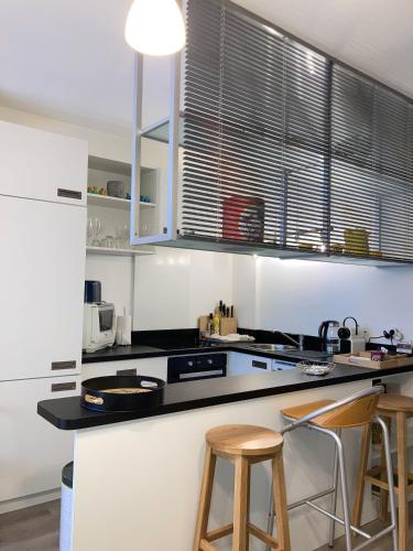 une cuisine avec un comptoir noir et deux tabourets dans l'établissement Le Central Victoria V -Central Point -55m2, à Nancy