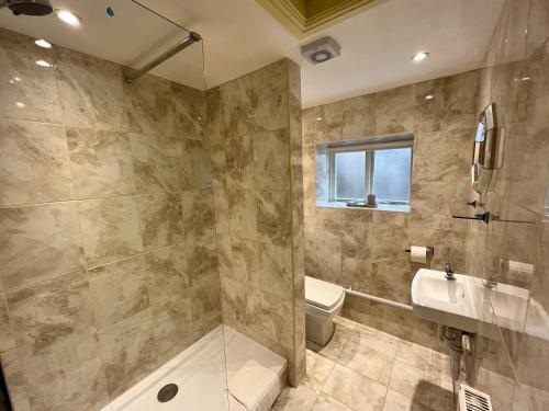 a bathroom with a shower and a toilet and a sink at Swan House Tea Room and Bed & Breakfast in Lydney