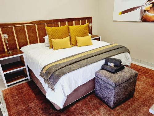a bedroom with a large bed with yellow pillows and a ottoman at The Hank Bethlehem Pty Ltd in Bethlehem
