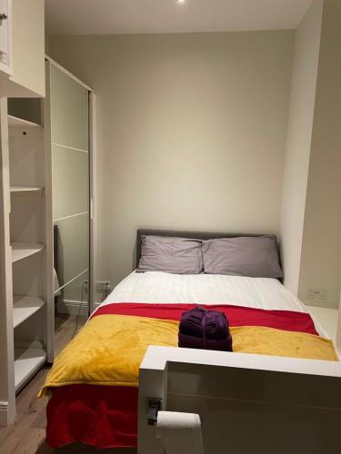 a bedroom with a bed with a yellow and red blanket at London Central 2 minutes away from train station in London