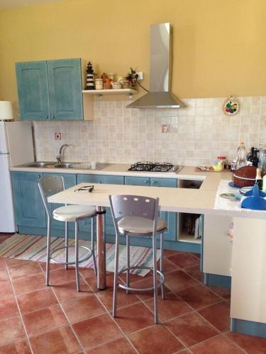 a kitchen with blue cabinets and a counter with stools at Fraschi Countryhouse in Carpignano Salentino