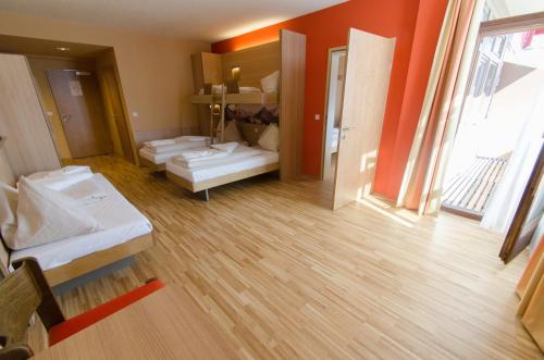 a room with three beds in a room with orange walls at JUFA Hotel Altenmarkt-Zauchensee in Altenmarkt im Pongau