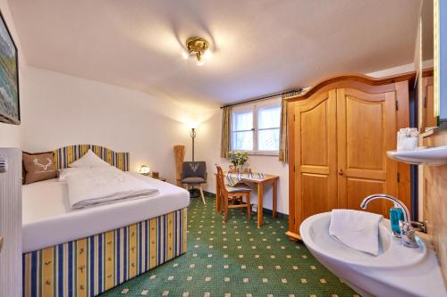 a bedroom with a bed and a sink and a desk at Gästehaus Angela in Garmisch-Partenkirchen