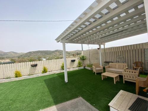 un patio con pérgola blanca y césped verde en צמרים סמר, en Nimrod