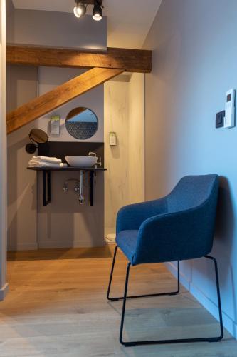 a blue chair in a room with a mirror at Oud Gemeentehuis in Poelkapelle
