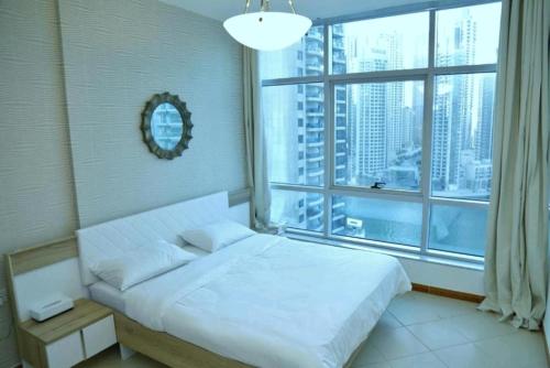 a bedroom with a white bed and a large window at Marina BestView 2 BedRoom Apartment in Dubai