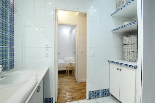 La salle de bains bleue et blanche est pourvue d'un lavabo et d'un miroir. dans l'établissement Apartment Saint Germain des Prés by Studio prestige, à Paris